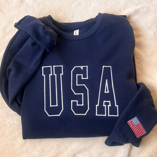 Navy blue sweatshirt with 'USA' printed on it, featuring an American flag patch, on a light background.
Patriotic 
4th of July 
